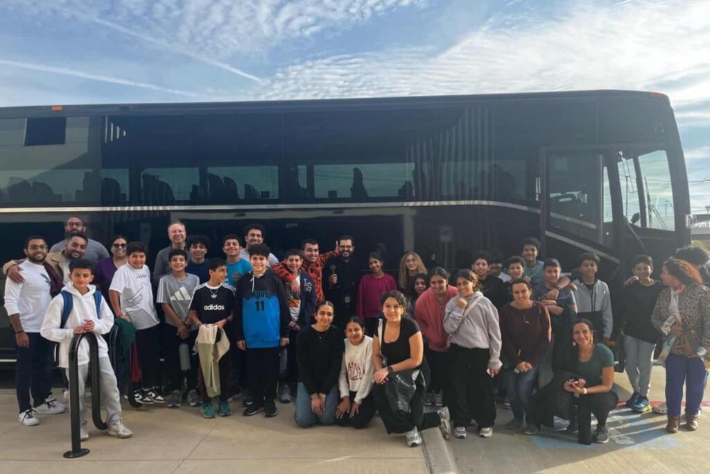 Large community group in front of JC Limo motor coach in Dallas for group transportation and event travel