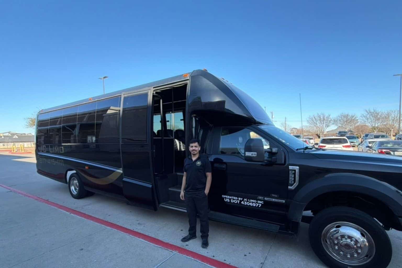 JC Limo driver standing beside luxury motor coach in Dallas providing professional group transportation service