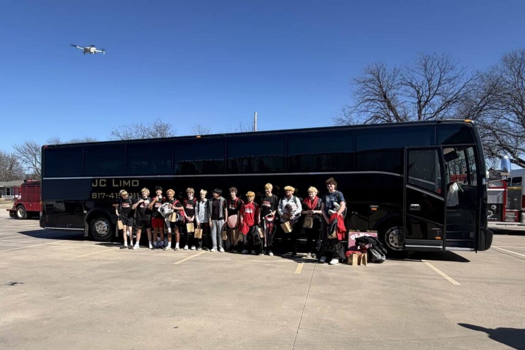 Sports team standing in front of JC Limo motor coach in Dallas for group transportation and event travel